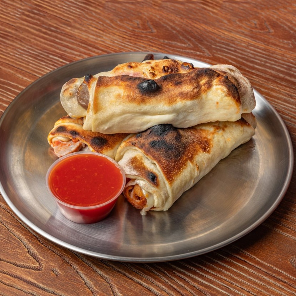 Three baked Italian rolls with melted cheese and meat, served with a side of red sauce.